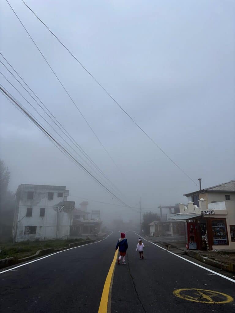 two girls walking down the middle of a street in a cloud