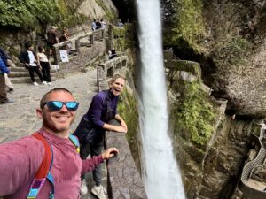 a man who is wet and a woman standing by a large waterfall