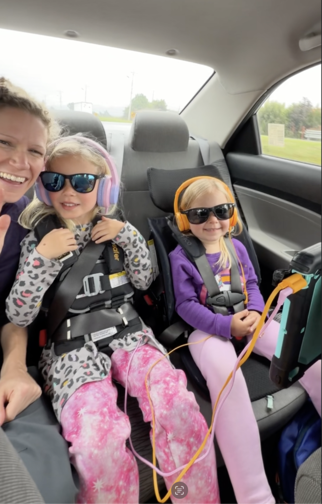three people in the back seat of a car smiling