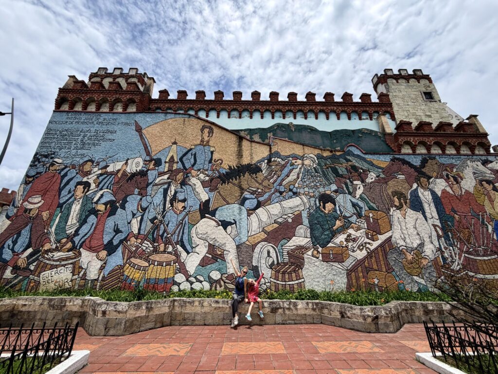 a woman and daughter posing in front of a massive mural taking up the entire side of a large building