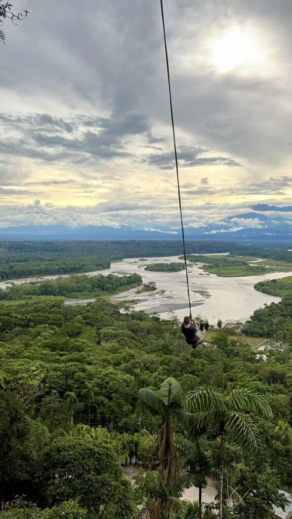 a person on a rope swing over a lush jungle
