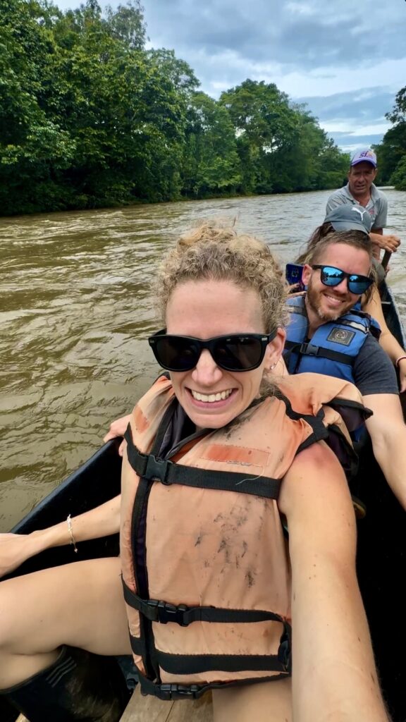 people in a canoe in a muddy water through a jungle