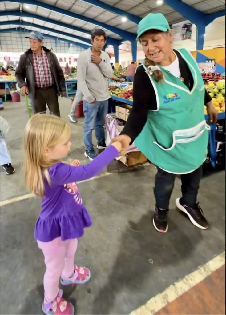 a girl handing a lady money for buying produce