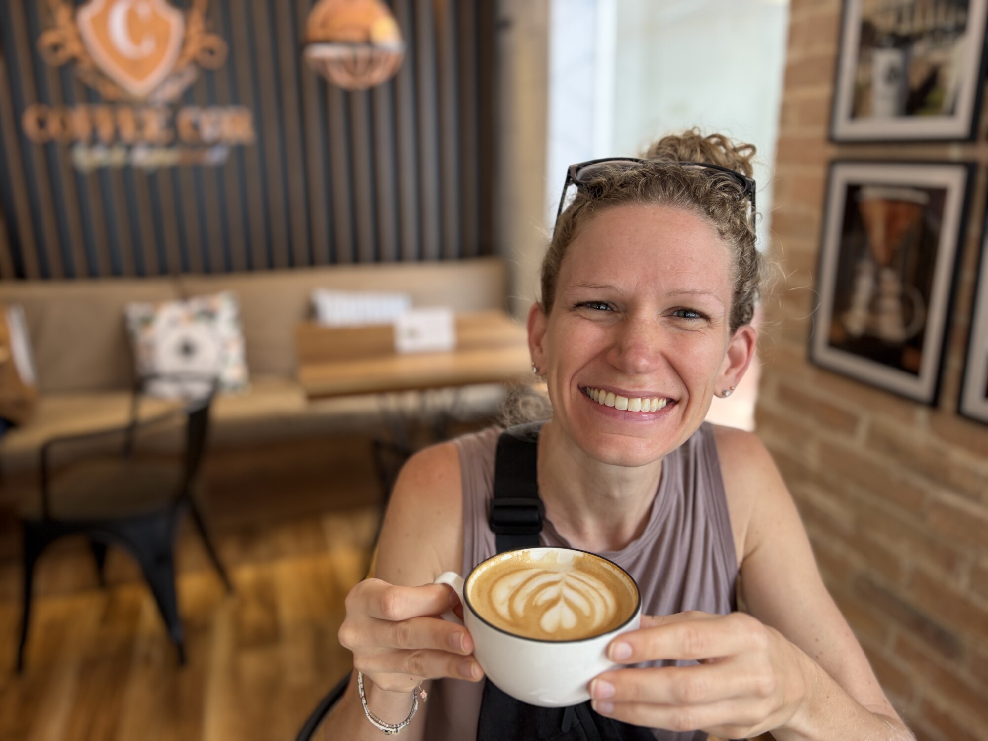 woman in bliss holding a latte style coffee in a cafe