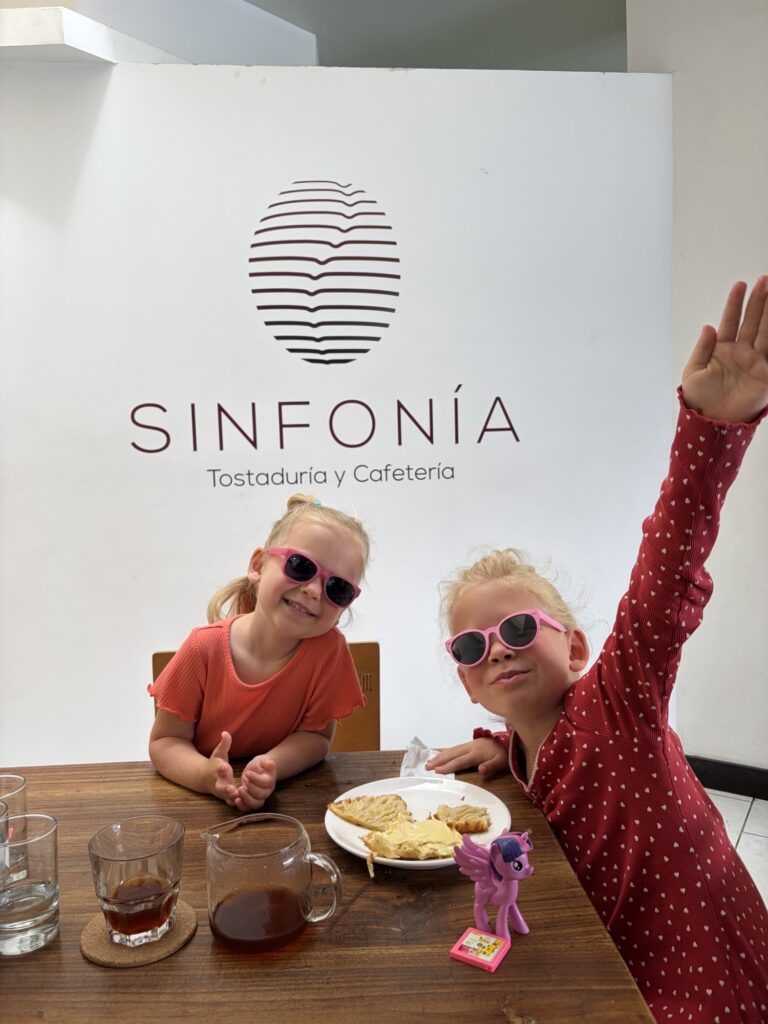 two gilrs wearing pink sunglasses posting in front of a cafe sign