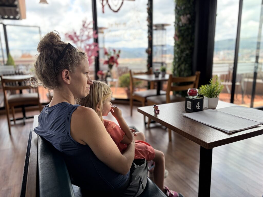 a girl and a mother at a cafe with views overlooking the city