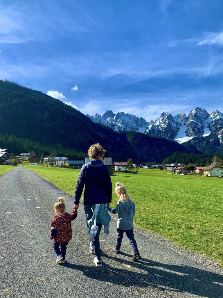 a mother walking with two kids with snow covered mountains in the background