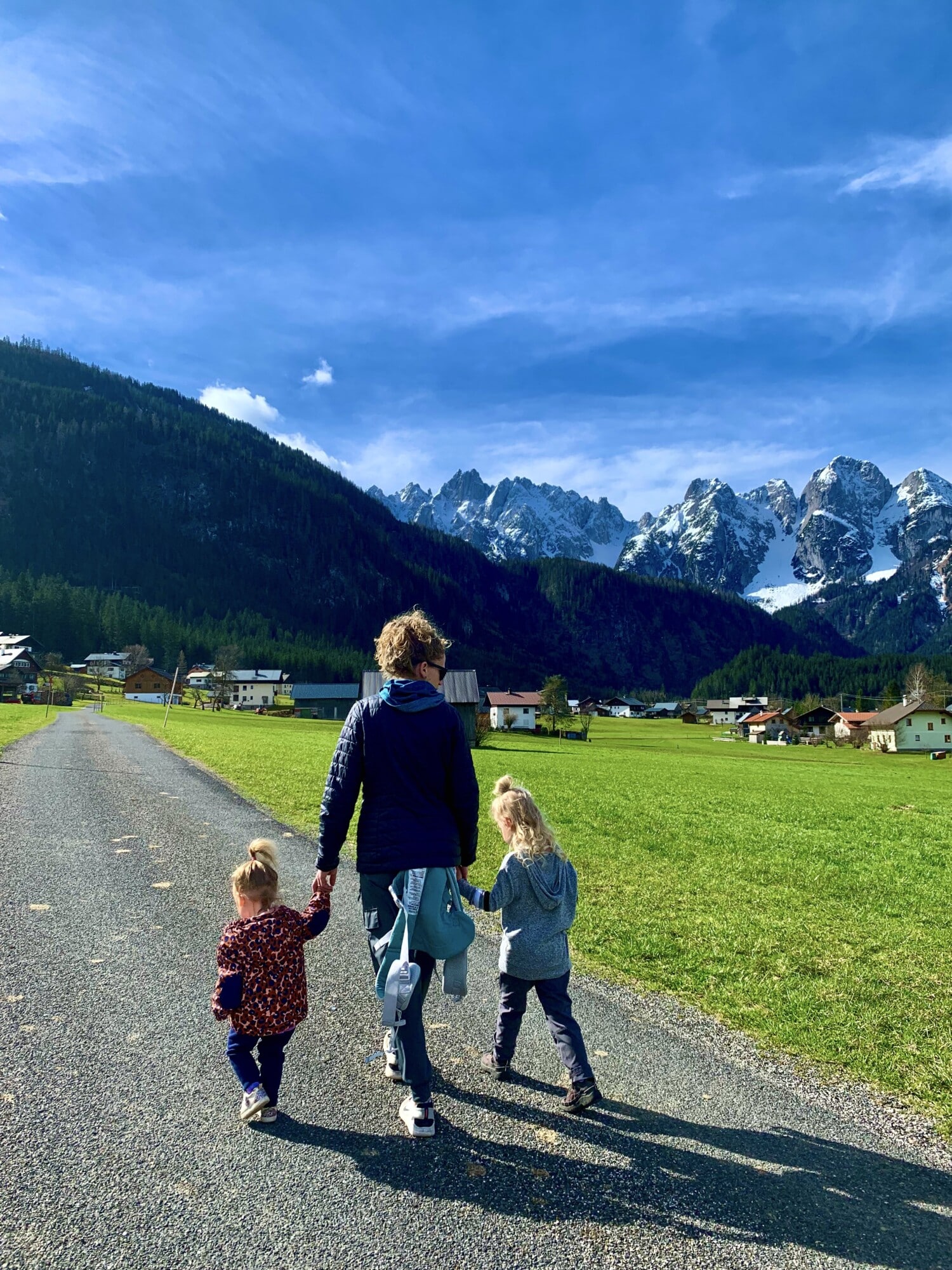 a mother walking with two kids with snow covered mountains in the background