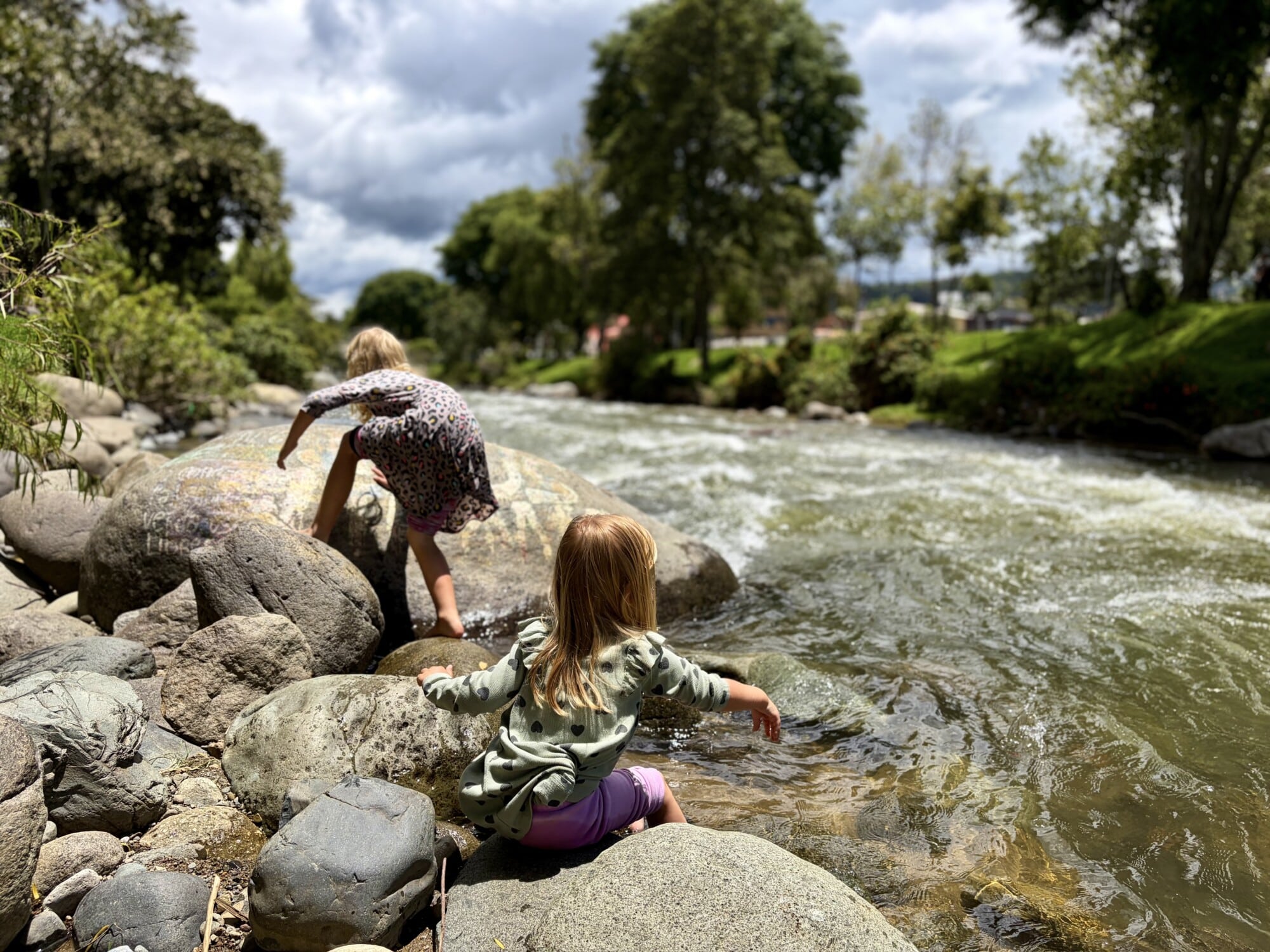 kids playing by a stream and climbing on boulders
