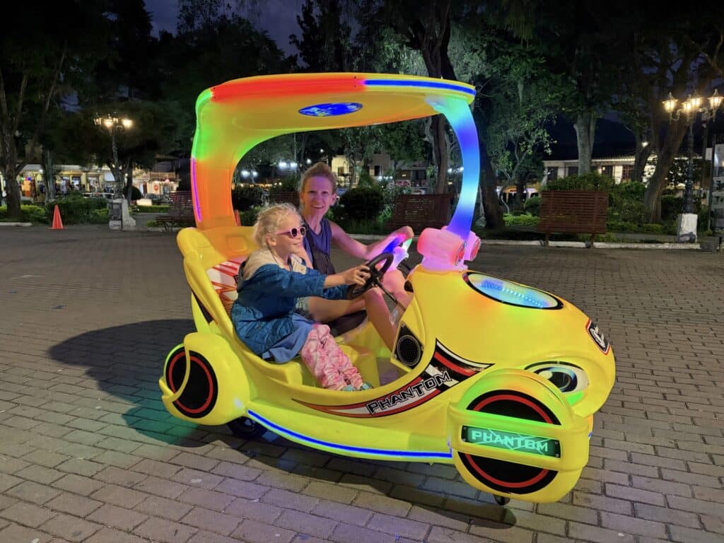 a girl and a mom driving a fun car that is lit up in different colors in the dark