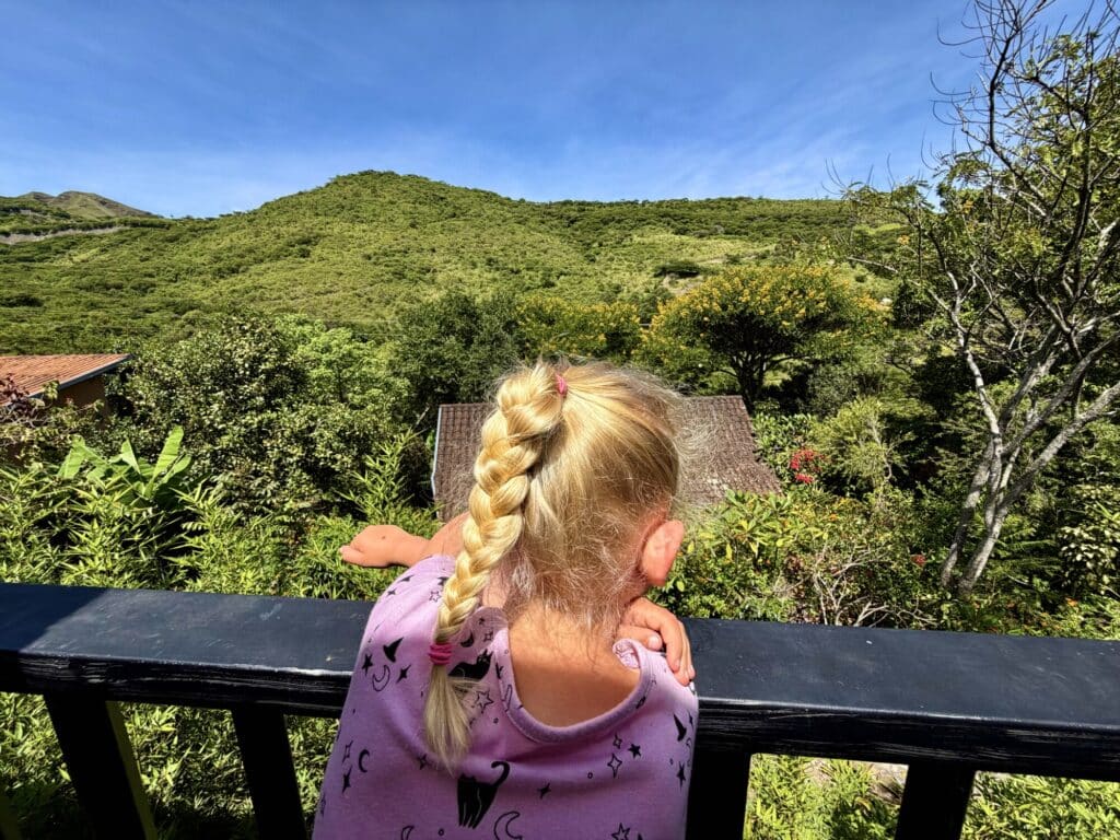 a girl overlooking a rolling mountain scenery with greenery