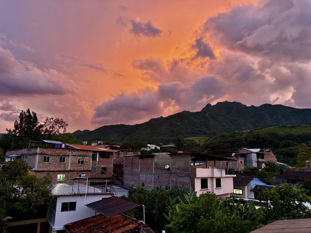 orange sunset with purples with mountains in the background and houses in the foreground
