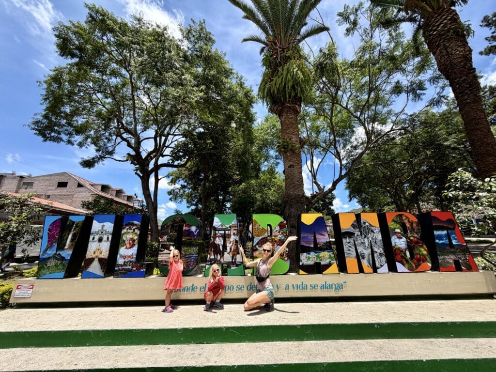 a woman and 2 girls standing in front of a sign that says Vilcabamba