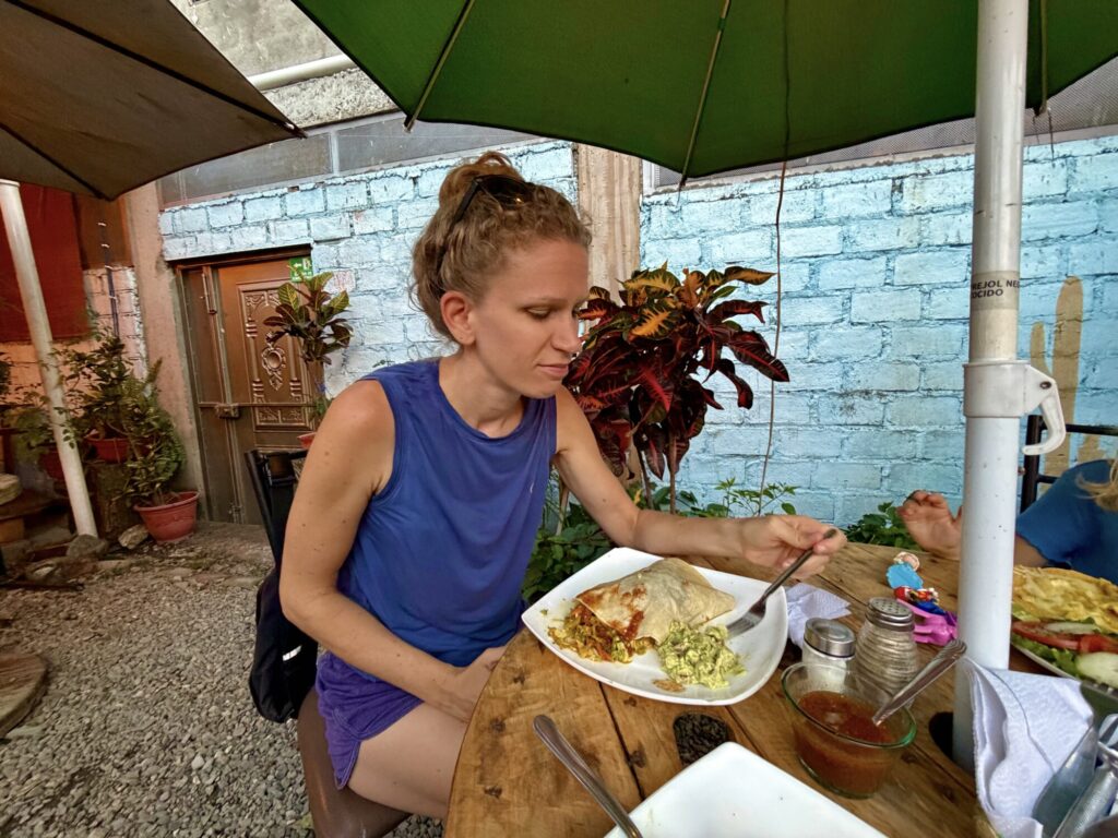 woman sitting outside at a restaurant eating a burrito