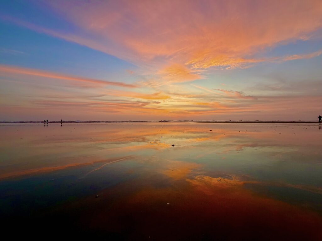 a sunset with yellows, oranges, purples that is mirrored on itself with calm ocean