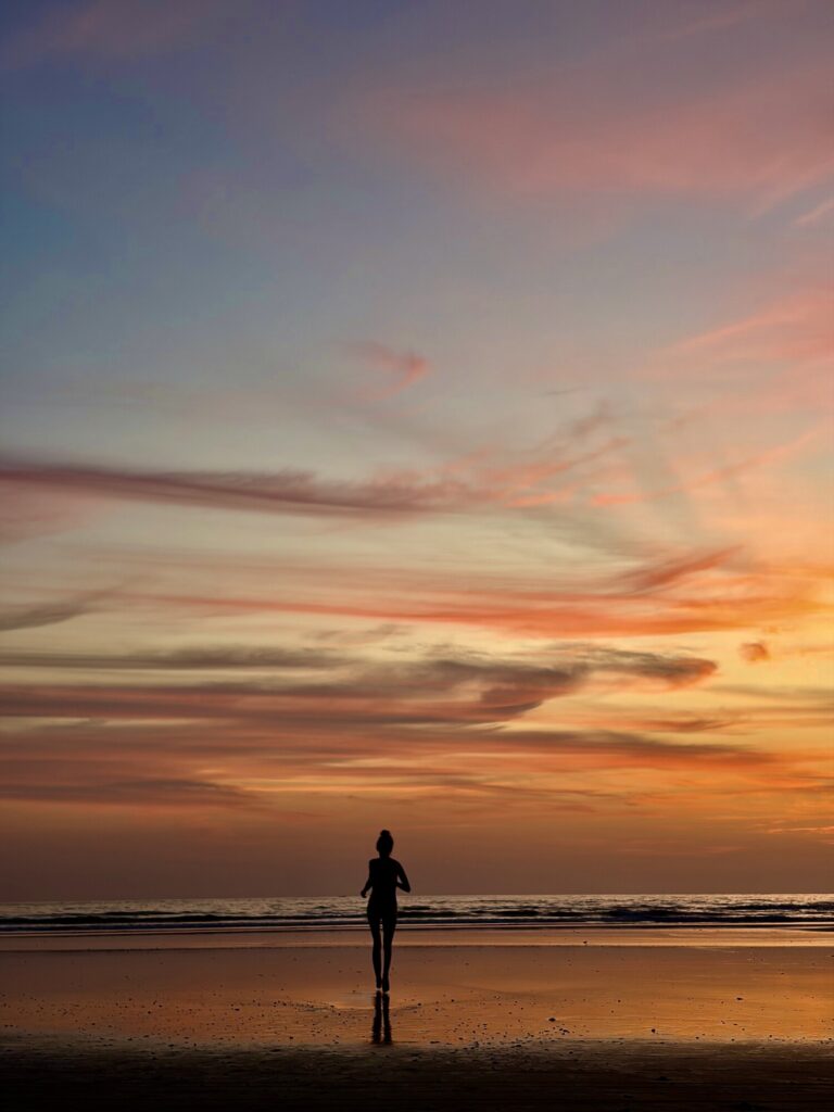 a woman running as a silhouette with a magnificent sunset