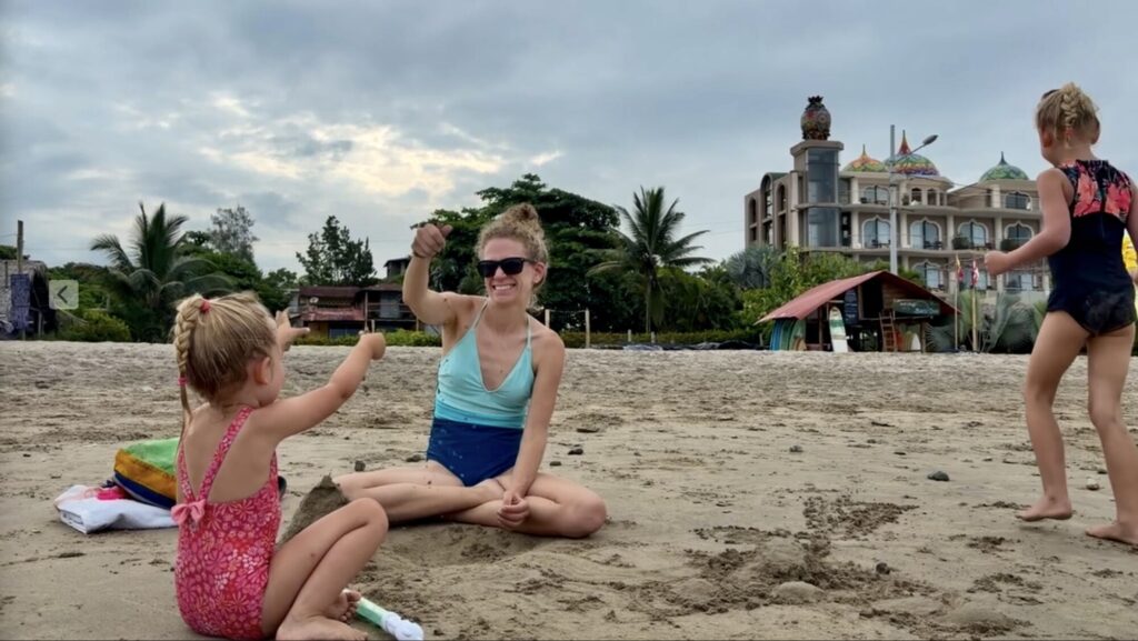 a mother and two kids playing at a beach