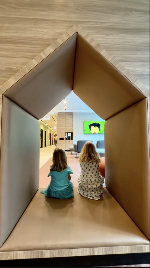 two girls in a house shaped cutout in a wall at a hospital