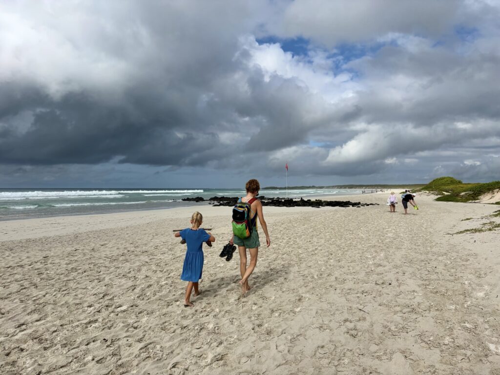 a woman and child walking along a white sand beach